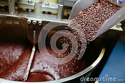 Artisan chocolate making, adding cocoa grits in the Melanger Stone Grinder Stock Photo