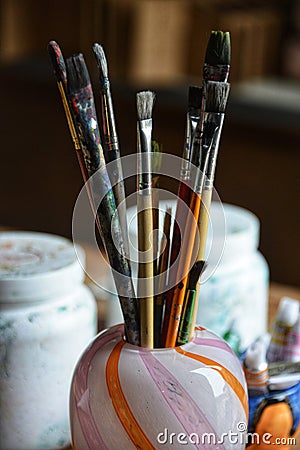 Artist brushes gathered in a pink and orange glass vase. Stock Photo