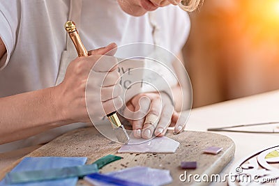 Artist cutting sheets of stained glass into small mosaic squares. Close-up Stock Photo