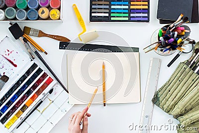 Artist drawing graphic sketch at sketchbook. Workplace, workspace. Top view photo of artistic tools lying on work-table Stock Photo