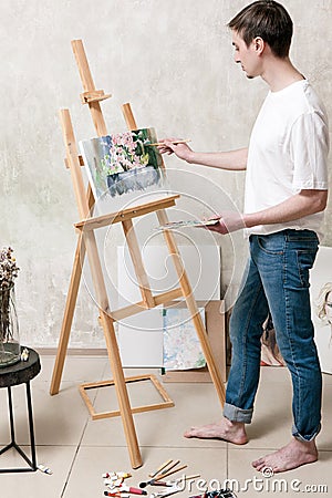 Artist draws a beautiful painting on easel Stock Photo