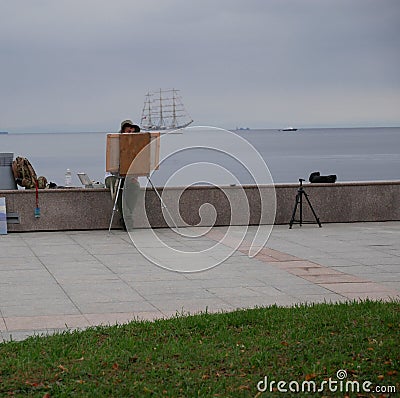 The artist draws a sketch of the picture sitting on the concrete fence of the sea embankment. Editorial Stock Photo