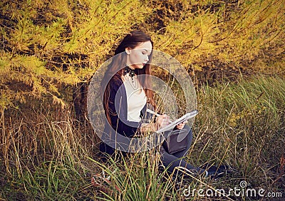 The artist draws in a sketchbook in the autumn forest Stock Photo