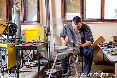 Artist is making figure by welding few metal wires in his workshop, barehanded Stock Photo