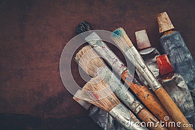 Artist paintbrushes, paint tubes closeup on brown canvas background. Stock Photo