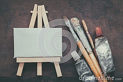Artist paintbrushes, paint tubes and small easel with canvas closeup. Top view. Stock Photo