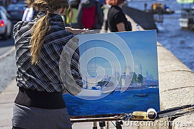 The artist paints a landscape on the Neva Embankment in St. Petersburg. A woman drawing a picture on the street Editorial Stock Photo