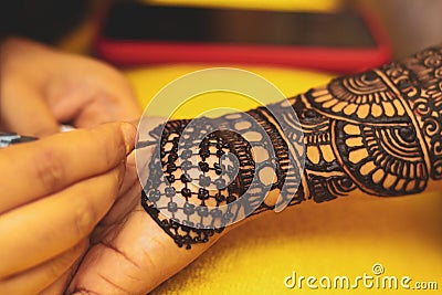 An artist performing mehandi or henna design on female hand Stock Photo