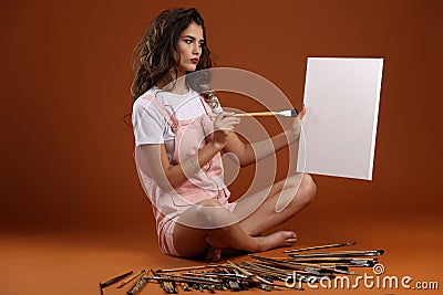 An artist in a pink jumpsuit with lots of brushes and a canvas Stock Photo