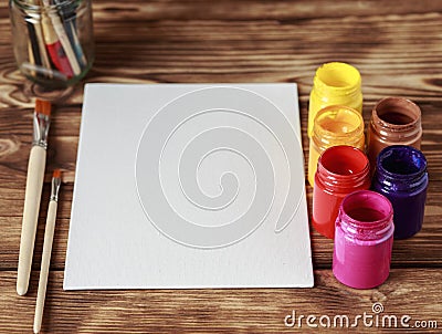 Artist`s workshop. Top view of paintbrushes palette and acrylic paints with white canvas. Set of brushes and oil paints. Art pictu Stock Photo