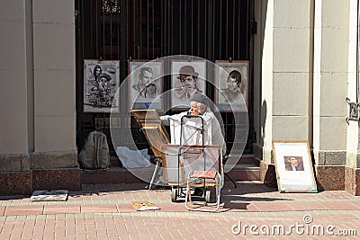 Artist on a spring day on the pedestrian Arbat street in Moscow Editorial Stock Photo