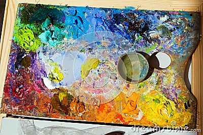 Artist wooden palette, mess of fresh bright colorful oil paints mixed in disorder, summer painting plein air Stock Photo