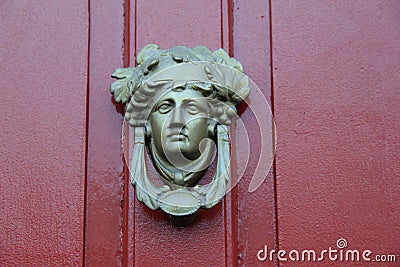 Artistic detail in elaborate knocker on red door of home Stock Photo