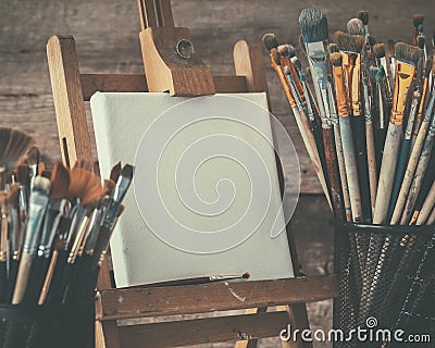 Artistic equipment: artist canvas on easel and paint brushes. Stock Photo