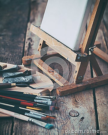 Artistic equipment: canvas on easel, palette and paint brushes. Stock Photo