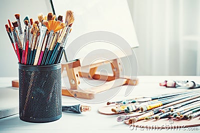 Artistic equipment: easel, brushes, paints and empty canvas. Stock Photo