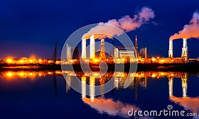 Industrial landscape with smoking chimneys and reflection in water at night Stock Photo