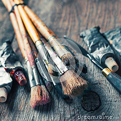 Artistic paintbrushes, tubes of oil paint, palette knife on old Stock Photo