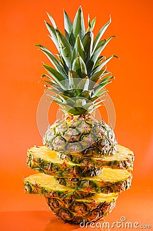 Artistic sliced, standing pineapple on orange background, vertical shot Stock Photo