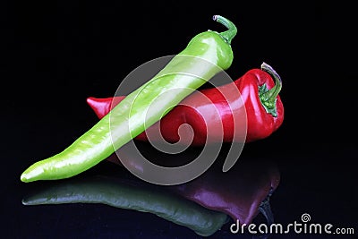 Artsy peppers red green hot strong pepper paprika on isolated black mirror mirrored reflective background. Stock Photo