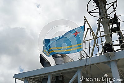 Aruba flag flutters on the wind on navigational mast of bridge of merchant container vessel during mooring in Barcadera. Stock Photo