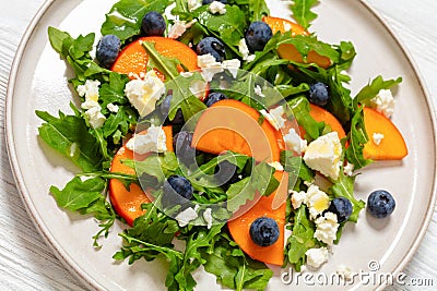 arugula persimmon cheese berries salad, top view Stock Photo