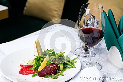 Arugula with salmon, brie cheese, ground pear and almonds and a glass of red wine. Place for text Stock Photo