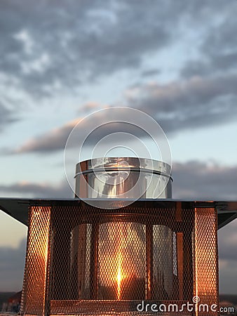 A metal container atop a roof reflects a warm and powerful sunset Stock Photo