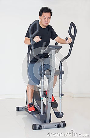 Asain Man Doing Exercises On Elliptical Cross Trainer. Stock Photo