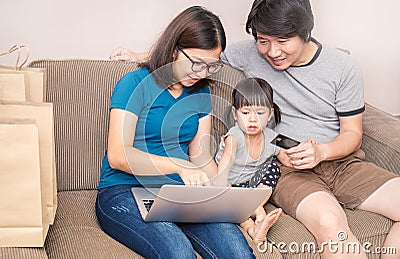 Asain parents and their daughter are doing shopping online using laptop Stock Photo