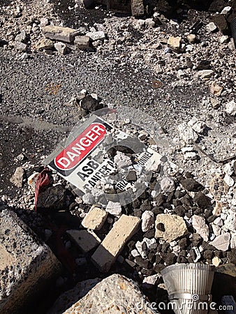 Asbestos warning sign laying among asbestos debris Stock Photo