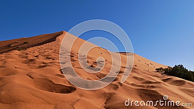 Ascent to a giant sand dune with footprints in the sand seen from the ground in Erg Chebbi near Merzouga, Morocco, Africa. Stock Photo