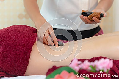 Asia beauty woman lying down on massage bed with traditional balinese hot stones along the spine at Thai spa and wellness center, Stock Photo