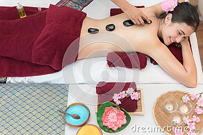 Asia beauty woman lying down on massage bed with traditional hot stones along the spine at Thai spa and wellness center, so relax Stock Photo