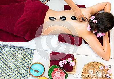 Asia beauty woman lying down on massage bed with traditional hot stones along the spine at Thai spa and wellness center, so relax Stock Photo