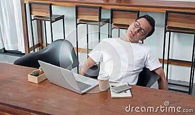 asia casual man sit back feel tired from work at laptop in coffee shop,stress business concept,work outside office,work at home. Stock Photo