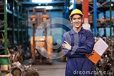 Asia engineer man worker wears a safety helmet and holding tablets. Crossed arm and standing in the automotive spare parts Stock Photo