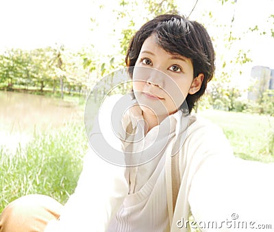 Asia girl sitting smile portrait and selfie under big tree in the garden park. Stock Photo