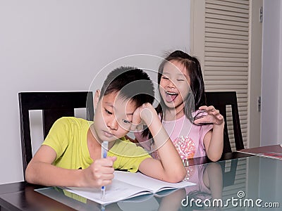 Asia little sister ridicule her brother studying and doing his h Stock Photo