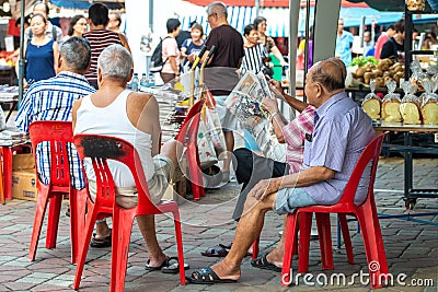 Asia / Singapore - Nov 9, 2019 : Group of ages mature adult Asian men relaxing in outdoor weekend, reading newspaper passing time Editorial Stock Photo