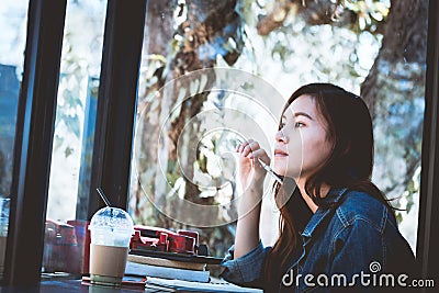 Asia teenage sitting in thinking alone with make a note in cafe Stock Photo