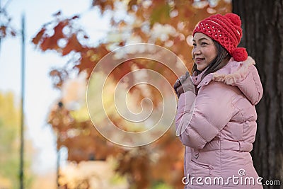 Asia woman feel cold in the park wearing winter accessories, pink sweater Stock Photo