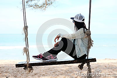 Asia woman sitting alone on wooden chair rope on beach looking t Stock Photo