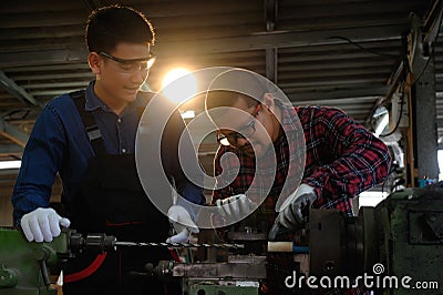 Asian apprentice young engineer discussion with technician on the job, Studying machine maintenance for drilling holes in wood. Stock Photo