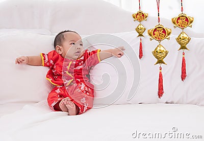 Asian baby boy Chinese Cheongsam costume toddler lie down on bed at home smiling laughing good humored infant Chinese boy laugh Stock Photo