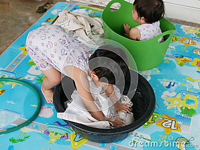 Asian baby girl left soaking clothes in water to wash it at home Stock Photo