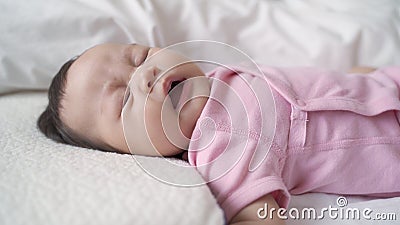 Asian baby infant laying down on white soft bed sneezing and smile. 3 months old baby facial expression Stock Photo