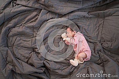 Asian baby infant wearing gloves and socks sleeping on gray bed. studio shot. Stock Photo