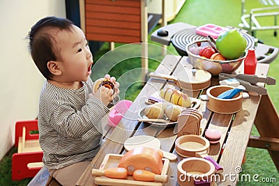 Asian baby playing with camping gear toy tools on the wooden table Stock Photo