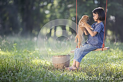 Asian baby on swing with puppy. Stock Photo